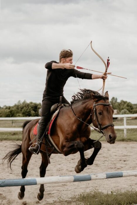 a man shooting an arrow while riding a horse