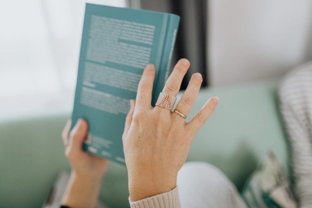 a person with finger rings holding a green book - topic: The Best Free AI Description Generators