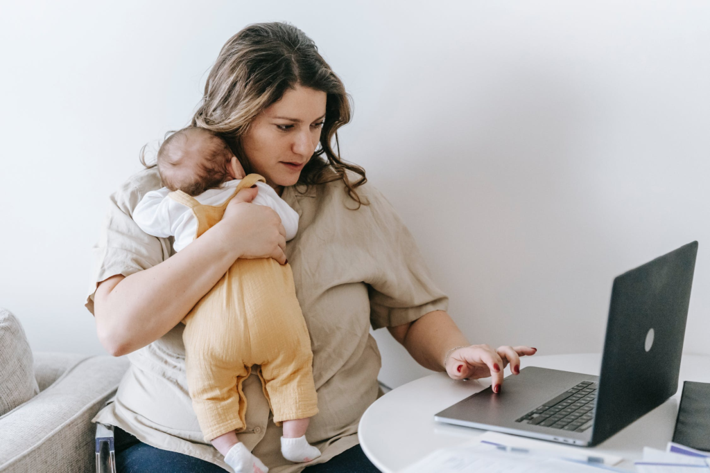 Virtual Assistance For A Flexible Schedule. pic of a mom holding her baby while using a laptop.