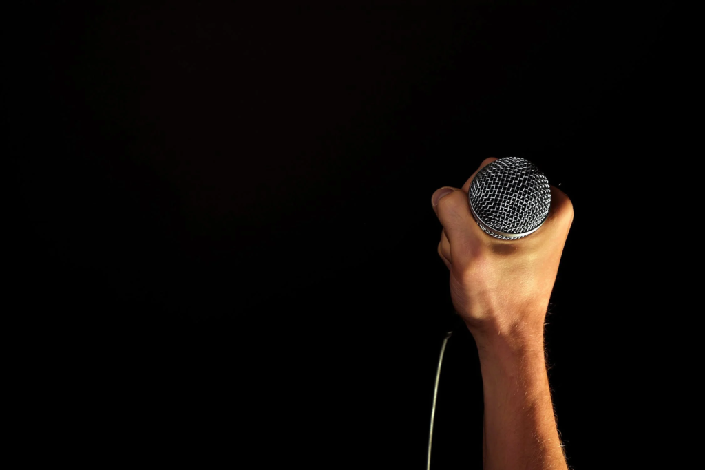 most profitable hobbies: Comedy. pic of a hand holding a mic