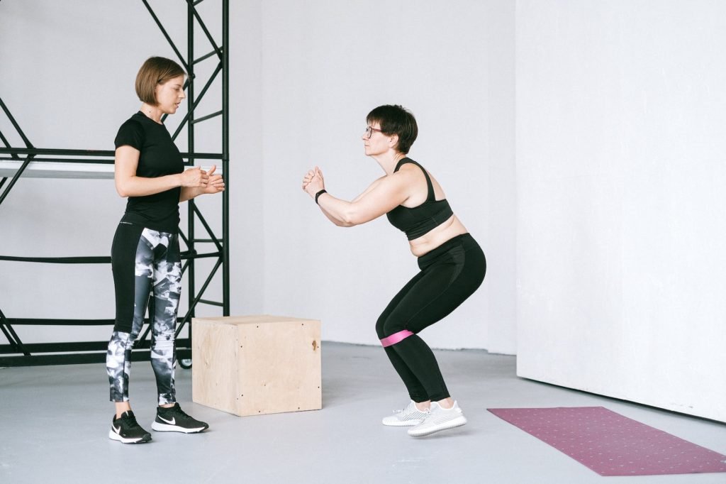 How to make money online as a fitness coach: a woman supervising an elderly woman exercise