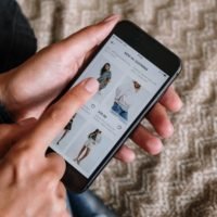 Les niches les plus rentables du Dropshipping - pic: fille tenant un téléphone parcourant une boutique de commerce électronique en ligne