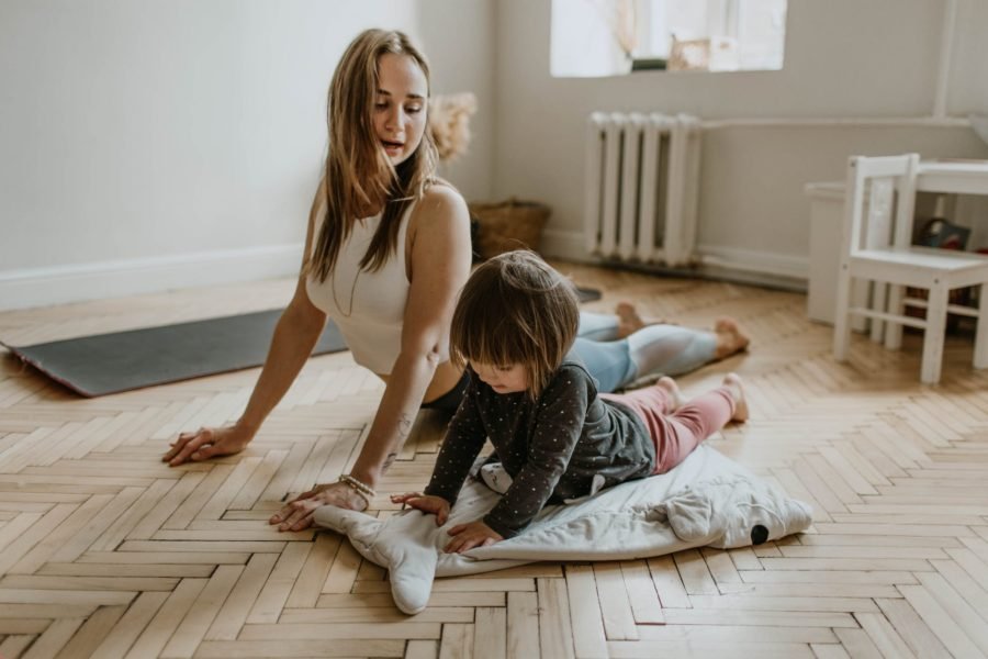 9. Remise en Forme à Domicile - pic: femme portant un haut sans manches blanc faisant du sport/yoga à la maison avec un enfant