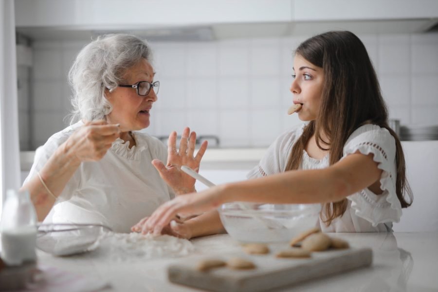 3. Cooking or Baking: pensive grandmother with granddaughter having interesting conversation while cooking together in light modern kitchen
