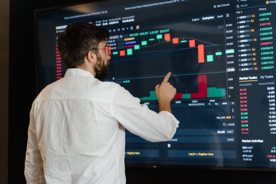 man in white dress shirt analyzing data displayed on Stock Market screen