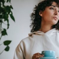 pensive woman with hot beverage at home - topic: Best Free AI Answer Generators (Writesonic User Guide)