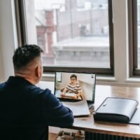 tutor having video call on netbook with student near documents