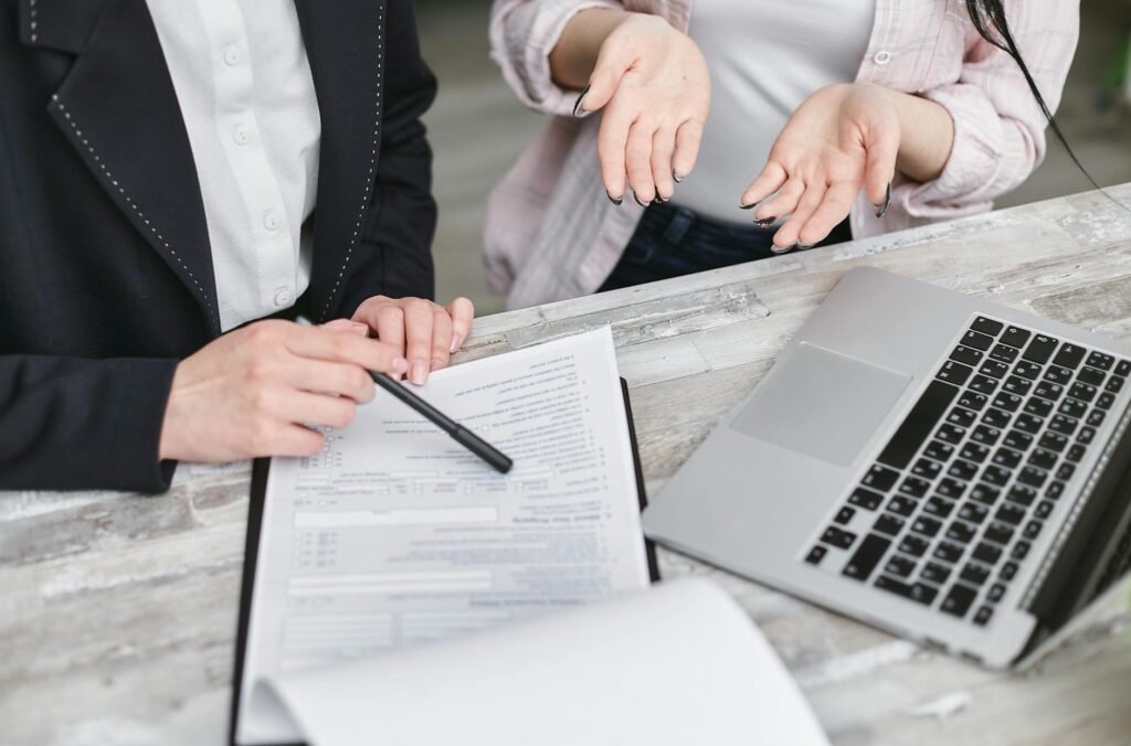 Two individuals engaged in a professional consultation with documents and a laptop on a wooden desk - Apostille services in California